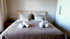 A neatly made bed with patterned bedding and two rolled towels.