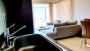 A modern kitchen with a sink and a dining area with a sofa and table.