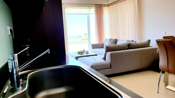 A modern kitchen with a sink and a dining area with a sofa and table.
