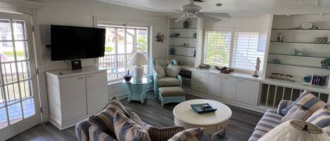 A living room with a sofa, armchairs, a coffee table, and a TV.