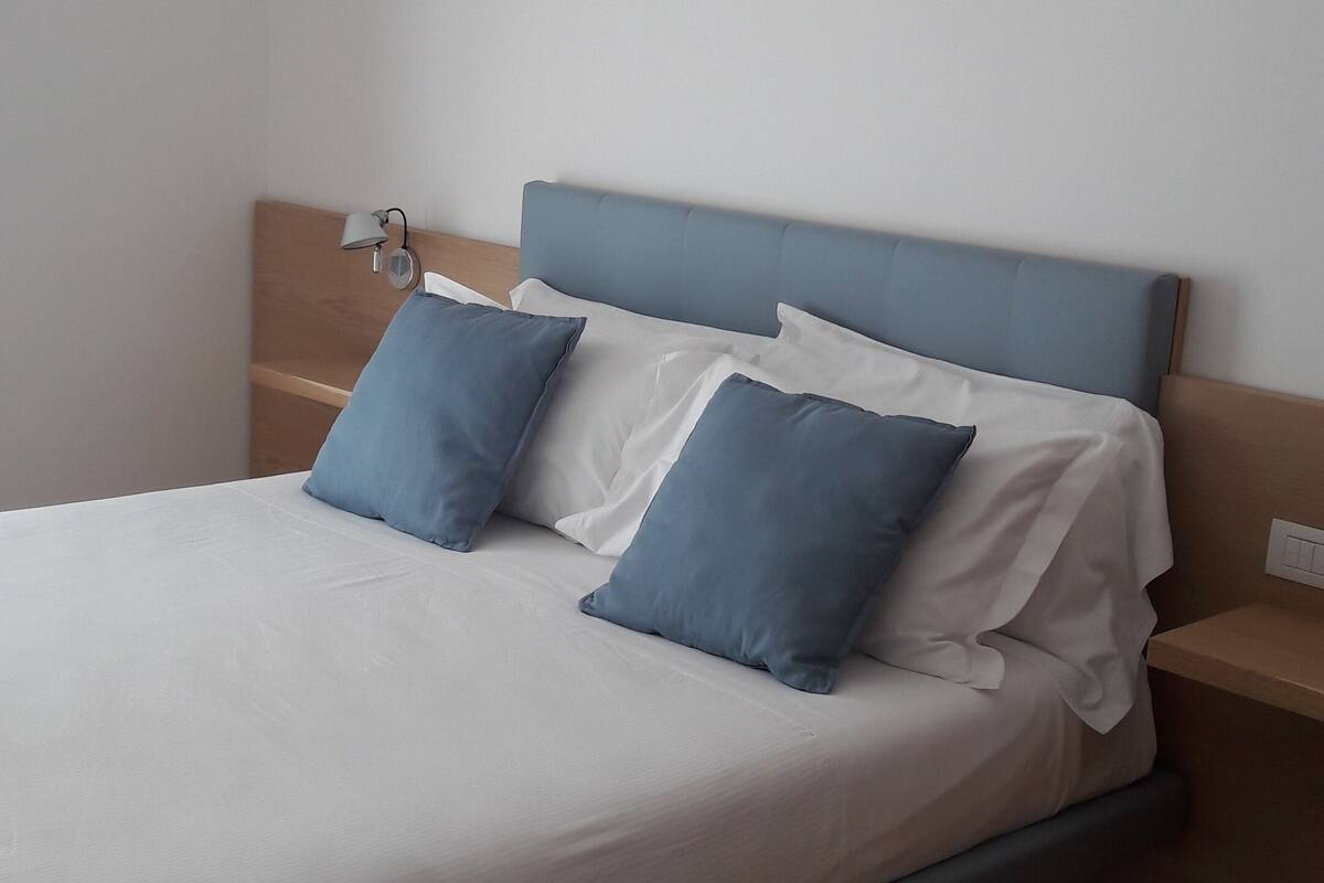 A bed with a wooden headboard, white bedding, and two blue pillows.