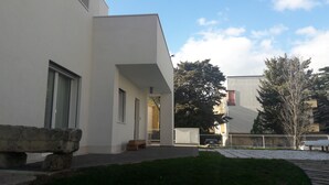 Ein modernes Gebäude mit flacher Fassade, großen Fenstern und einer Steinstruktur am Eingang.