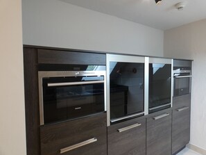Une cuisine équipée d’appareils électroménagers intégrés, notamment un réfrigérateur, un four et un four à micro-ondes.