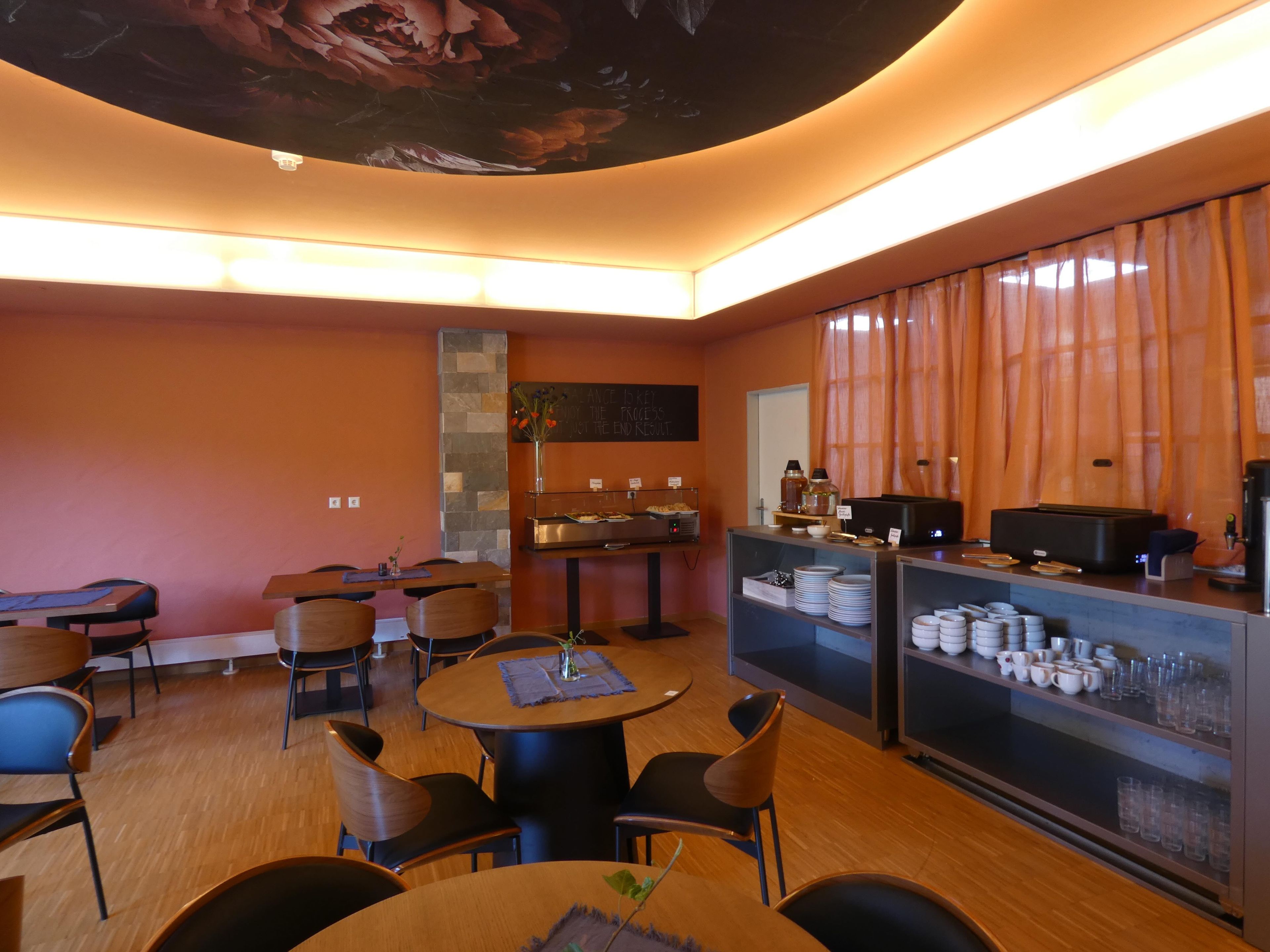 Ein Restaurant mit modernem Interieur, inklusive Bar, Sitzgelegenheiten und einer dekorativen Decke.
