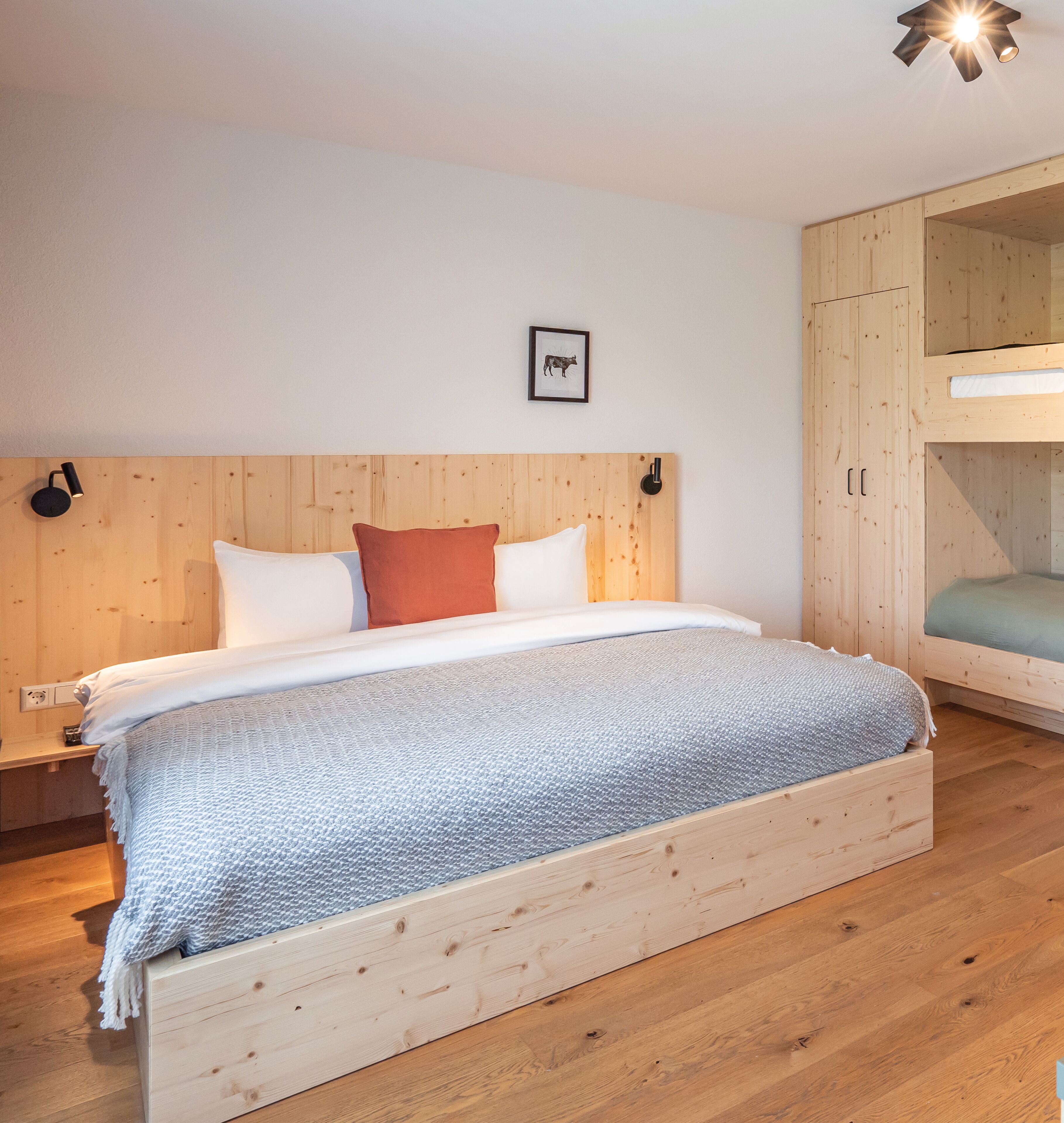 Quarto com beliche de madeira, uma mesa de cabeceira e um quadro pendurado na parede.