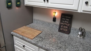 A kitchen with white cabinets, a granite countertop, a wooden cutting board, and a motivational quote sign. - THE " BOAT ANCHOR LOUNGE"  UPSCALE LUXURY (North Augusta)