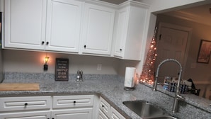 A kitchen with white cabinets, granite countertops, a stainless steel sink, and a decorative Christmas tree. - THE " BOAT ANCHOR LOUNGE"  UPSCALE LUXURY (North Augusta)