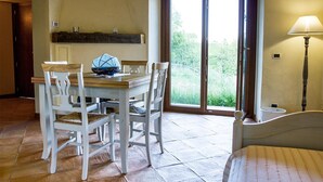 A dining area with a table and chairs, a lamp, and a view through a glass door. - Borgo Serafino (Paterno Calabro)