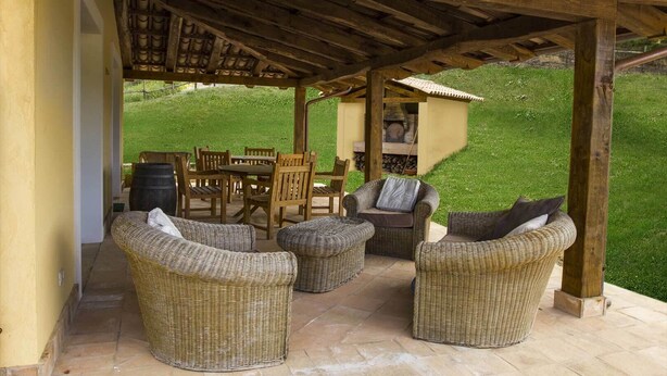 A covered patio with wicker furniture, a wooden table, and chairs. - Borgo Serafino (Paterno Calabro)