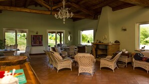 A rustic interior with wicker furniture, a fireplace, and a chandelier. - Borgo Serafino (Paterno Calabro)