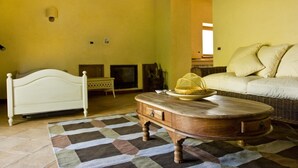 A room with a bed, a wicker sofa, a wooden coffee table, and a patterned rug. - Borgo Serafino (Paterno Calabro)