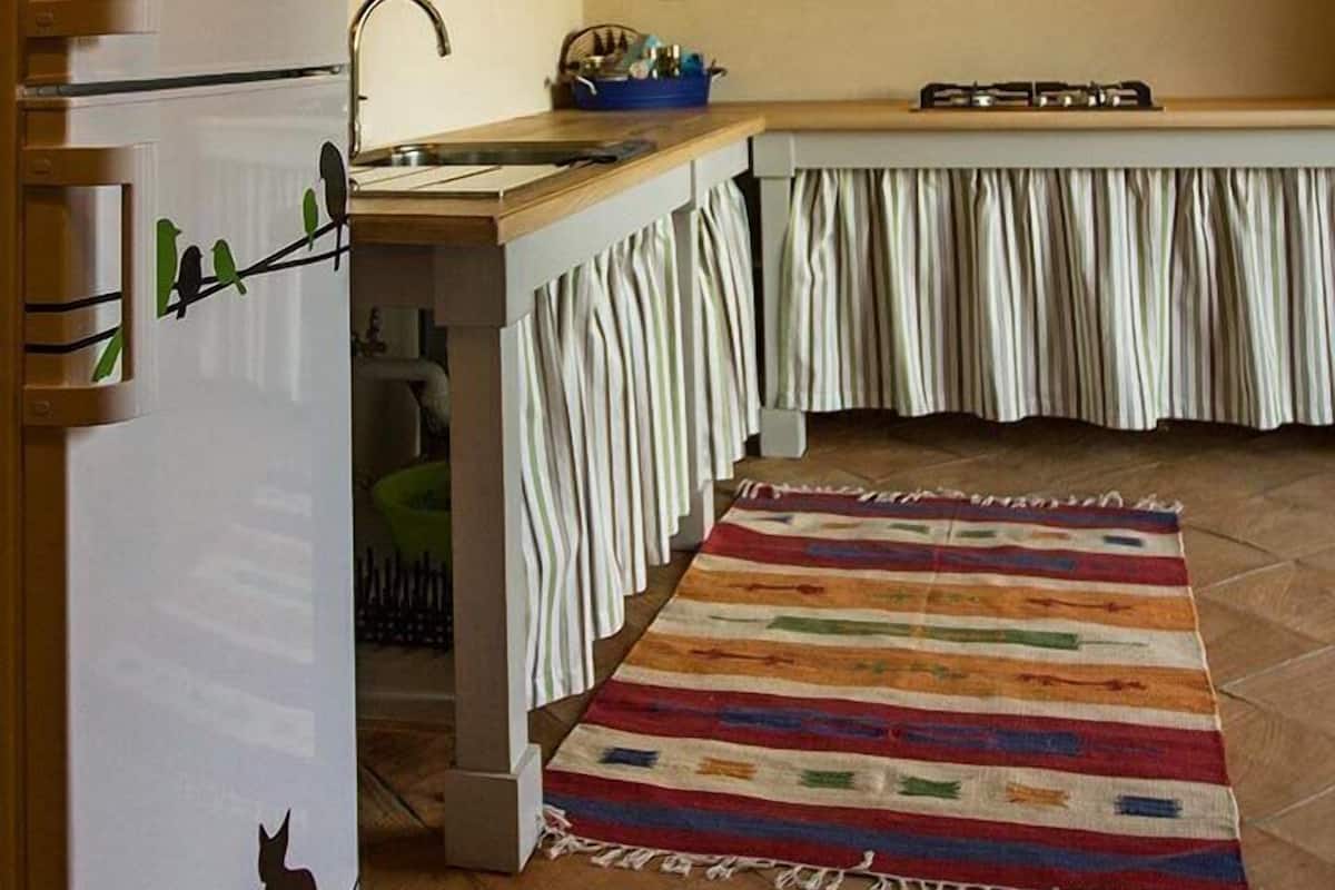 Eine kleine Küche mit Kühlschrank, Spüle und Gaskochfeld.