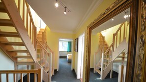 Un pasillo con escaleras de madera y un espejo grande que refleja las escaleras.