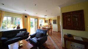 Una sala de estar con un sofá de cuero negro, una mesa de centro de madera y un comedor con mesa y sillas de madera.