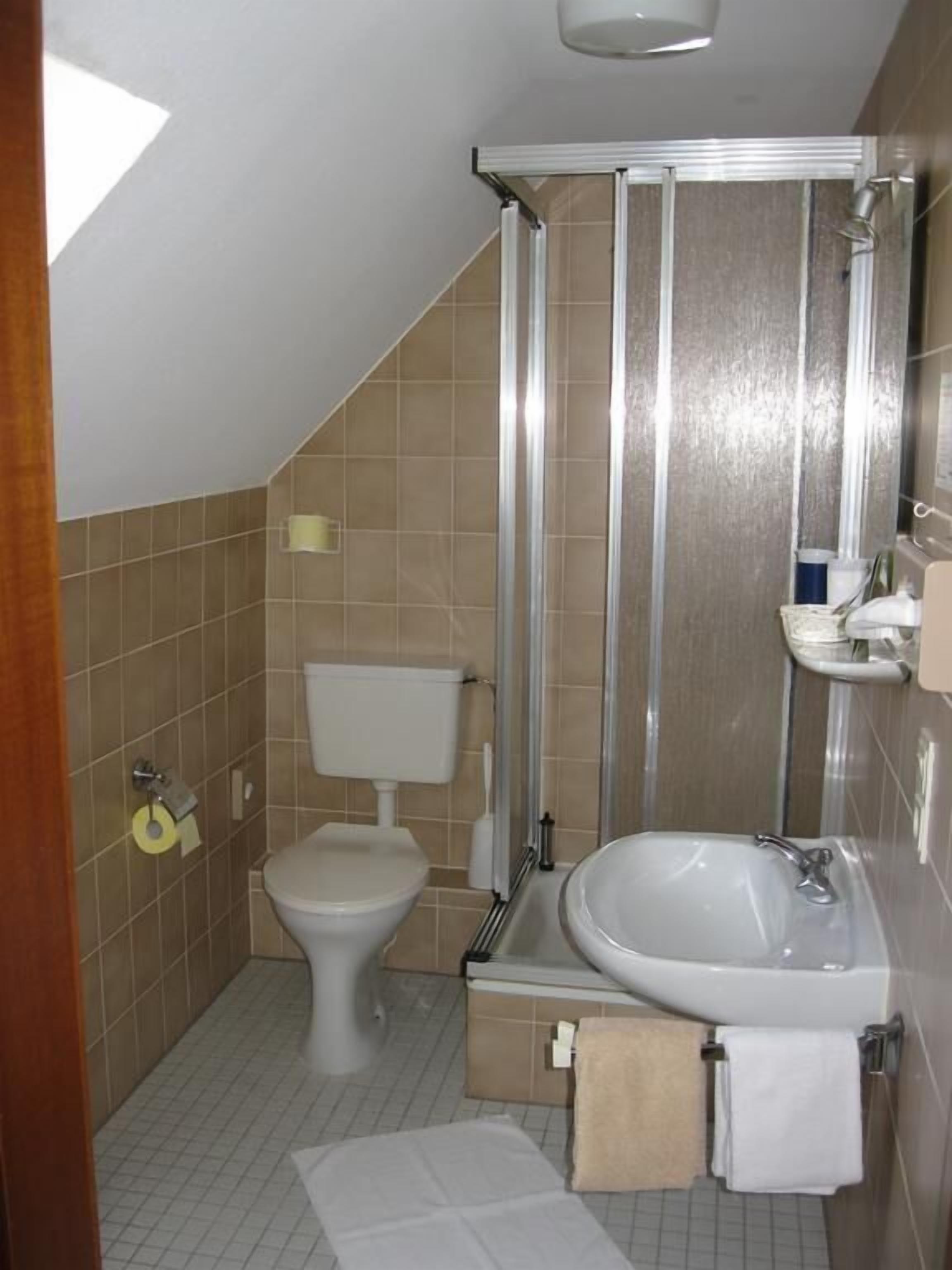 A small bathroom with a toilet, sink, and shower.