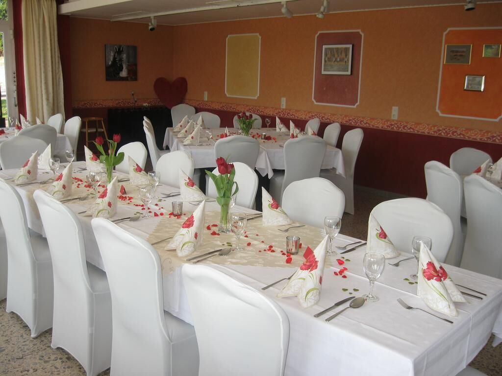 Una sala de banquet amb taules i cadires blanques, centrals florals i decoracions en forma de cor a les parets.