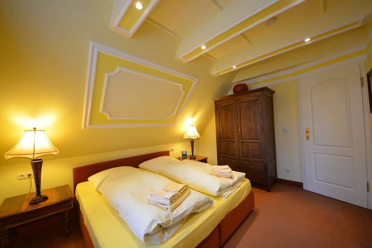 A hotel room with two beds, a wooden wardrobe, and a white door.