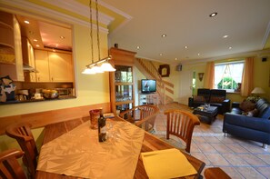 A dining area with a wooden table, chairs, and a TV in the background. - Reethäuser Boddenstr. 17 (Mönchgut-Granitz)