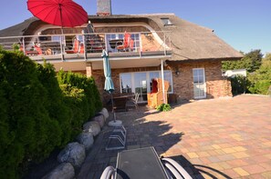 A two-story house with a balcony, a red umbrella, and a paved driveway. - Reet Hausteile Sonnenkliff und Kamp (Mönchgut-Granitz)
