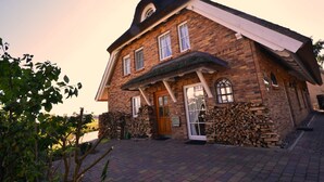 Een bakstenen huis met een puntige dakschild en een veranda, plus een houten deur.