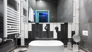 Une salle de bain moderne avec une baignoire sur pieds, un porte-serviettes, un miroir et un distributeur de serviettes.