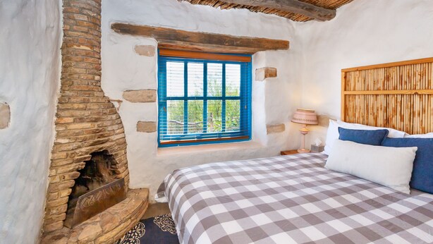 Ein rustikaler Raum mit einem karierten Bett, einem Steinkamin und einem hölzernen Kopfteil.