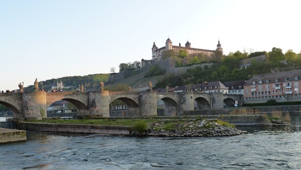 A stone bridge with arches over a river, leading to a castle on a hill. - Trendige Altbau Wohnung am Ringpark (Würzburg)