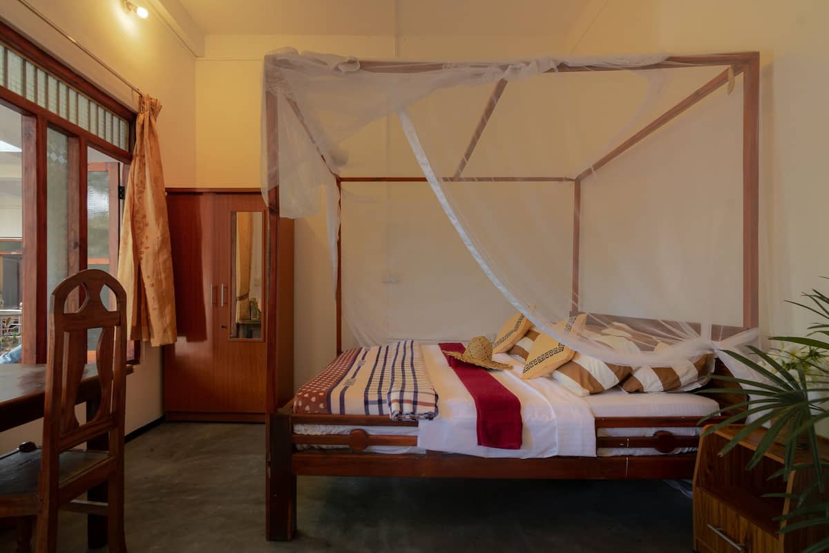Una cama con dosel, muebles de madera y una planta en maceta.