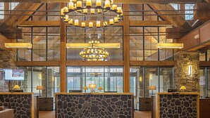 Eine Lobby mit Steinsäulen, Holzbalken und Kronleuchtern.