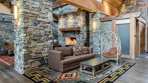 A cozy lounge area with a stone wall, a fireplace, a cushioned chair, and a patterned rug. - Amazing Paradise Point Resort in Hollister! (Hollister)