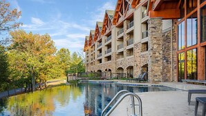 A hotel with a stone facade, multiple balconies, and a swimming pool. - Amazing Paradise Point Resort in Hollister! (Hollister)