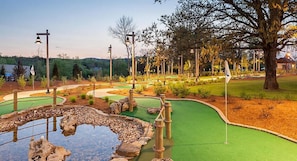 A miniature golf course with a pond, green fairways, and wooden structures. - Amazing Paradise Point Resort in Hollister! (Hollister)