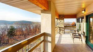 A balcony with a stone wall, wooden ceiling, and a view of a lake and trees. - Amazing Paradise Point Resort in Hollister! (Hollister)