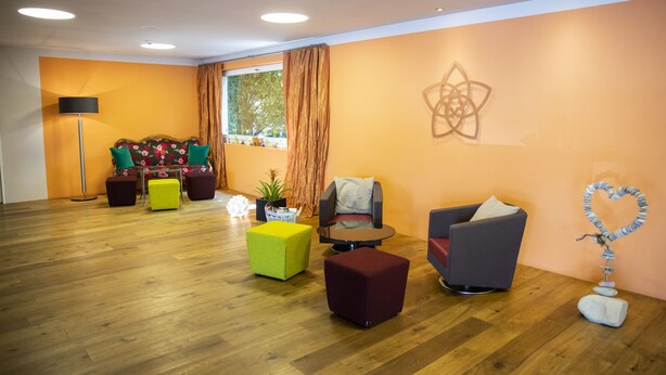 Un salon moderne avec un plancher en bois, un ensemble de canapés et un élément décoratif mural.