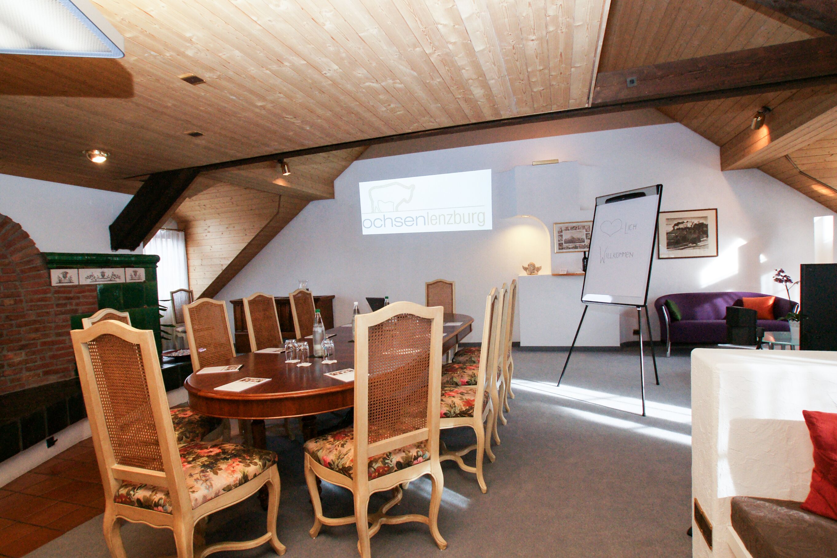 A conference room with a wooden table, floral chairs, and a whiteboard.