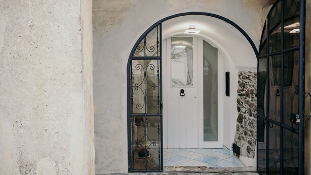 Un arco de entrada con puerta de cristal y pared de piedra.