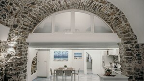 Un comedor con un arco de piedra, una mesa con sillas y vistas a la cocina y al comedor a través de un arco abierto.