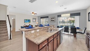 A modern kitchen with granite countertops, a built-in sink, and a dining area with a table and chairs. - Stunning villa, lake views-south facing pool - game room,  near Disney & golf (Davenport)