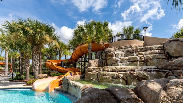 A water park with a large slide, a pool, and palm trees. - Stunning villa, lake views-south facing pool - game room,  near Disney & golf (Davenport)