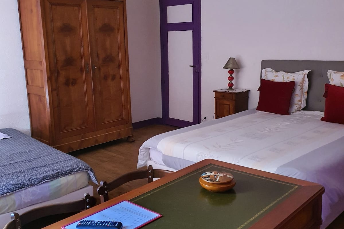 Une chambre à coucher comprenant un lit, une armoire en bois, un bureau avec une chaise et une table de chevet avec une lampe.