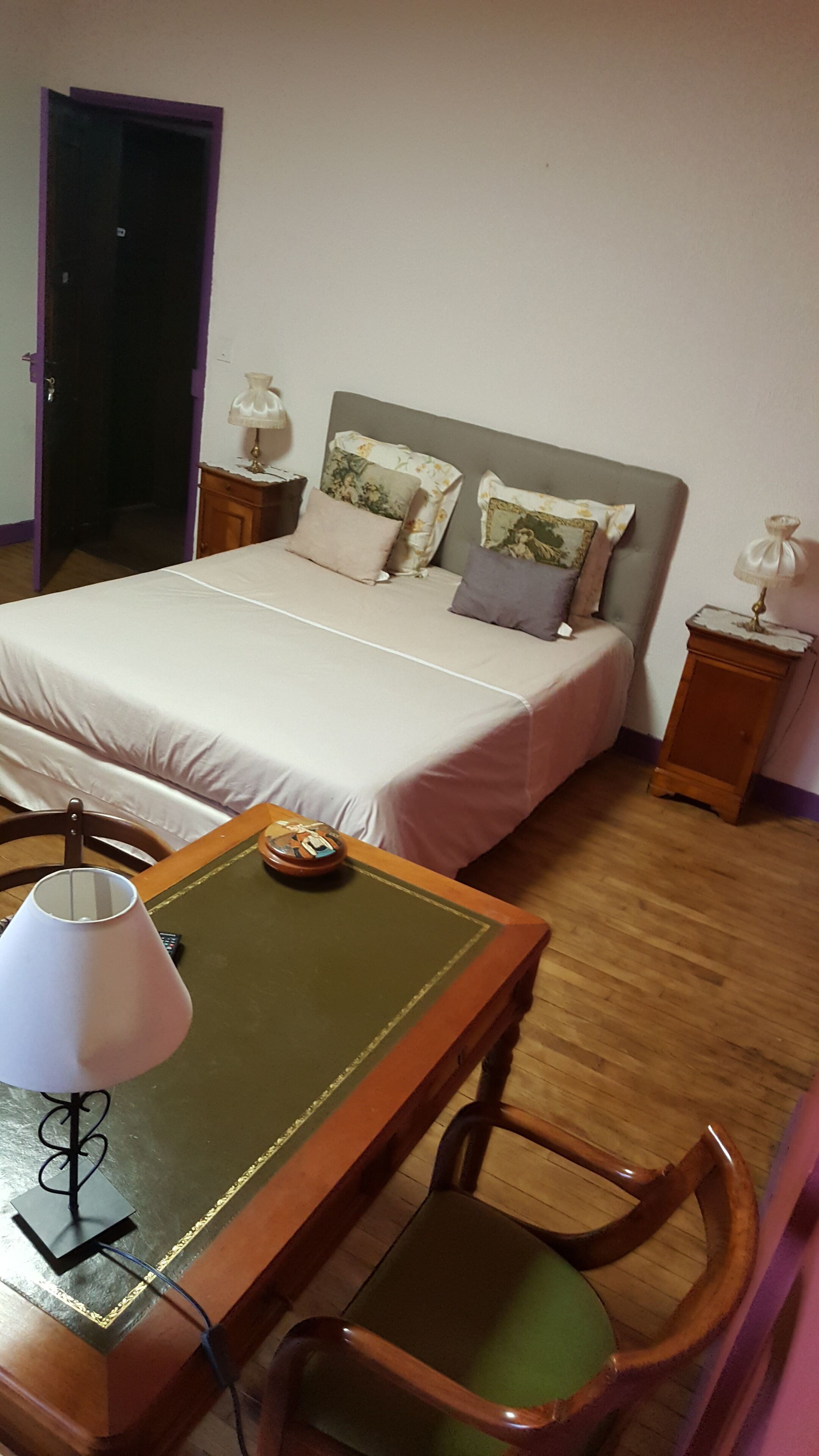 Un dormitorio con una cama, mesitas de noche, un escritorio con lámpara y una silla.