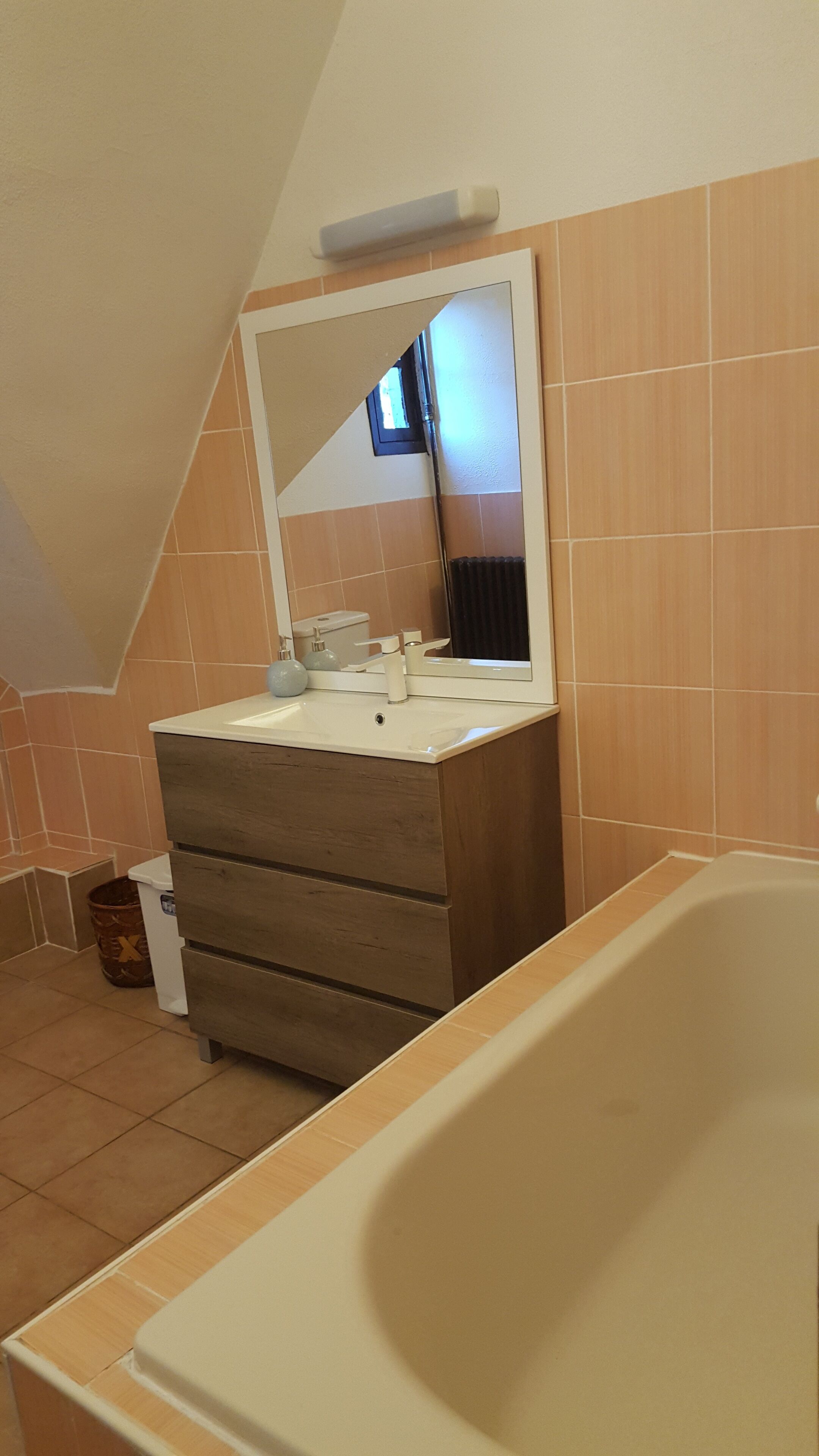 A bathroom with a wooden vanity, a white sink, a mirror, and a bathtub.