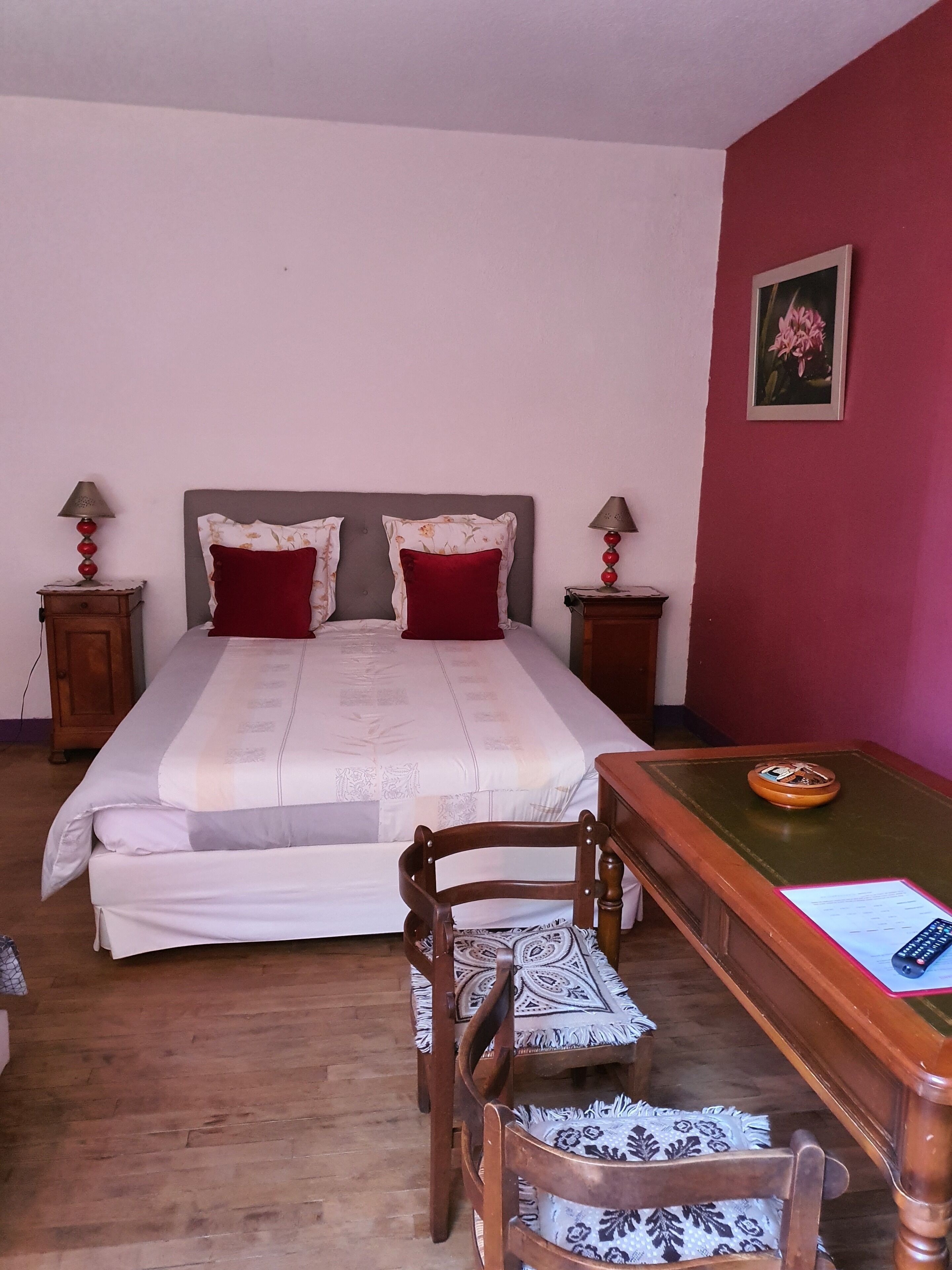 Un dormitorio con una cama, dos mesitas de noche, un escritorio con una silla y un cuadro en la pared.