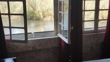 Una habitación con una cama, un escritorio y dos ventanas con vistas a un río.