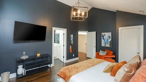 Un dormitorio moderno con una cama grande, un televisor de pantalla plana, una consola y un pasillo que lleva a otra habitación.