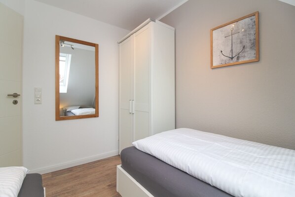 Una camera da letto con un letto, un armadio, uno specchio e un'opera d'arte appesa al muro.