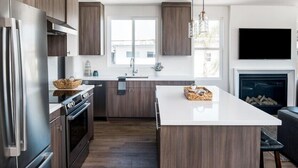 A modern kitchen with dark wood cabinets, stainless steel appliances, and a central island. - Book now Summer is here— Pet,2BR/2BA, 2 Parking (Newport Beach)