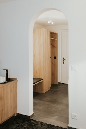 A hallway with a wooden bench, a white door, and a wooden wardrobe.