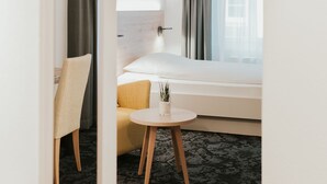 A modern hotel room with a bed, a small round table, a chair, and a mirror. - Gartenhaus by Ochsen Lenzburg (Lenzburg)