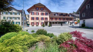 A traditional European hotel with a central courtyard, a sign reading "HOTEL OCHSEN," and a mix of residential and commercial buildings in the background. - Gartenhaus by Ochsen Lenzburg (Lenzburg)